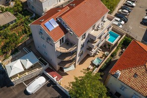 Un immeuble à plusieurs étages doté d’une piscine, de balcons et d’un espace extérieur aménagé avec des sièges.