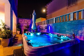 A hot tub with multiple jets, surrounded by potted plants and a stone wall.