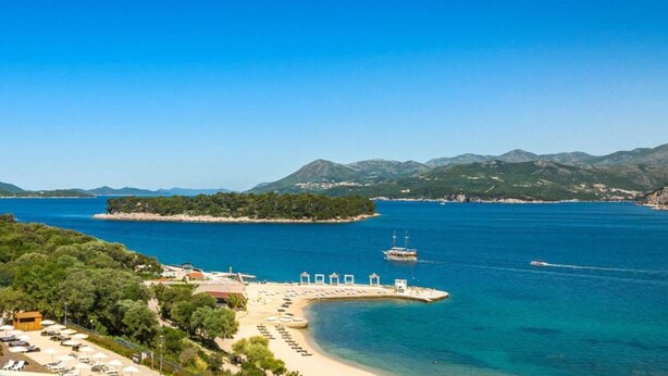 Ein Küstenort mit Strand, klarem blauen Meer und einem Bergpanorama.