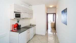 A compact kitchen with a microwave, coffee maker, and sink. A hallway leads to a balcony with a view.