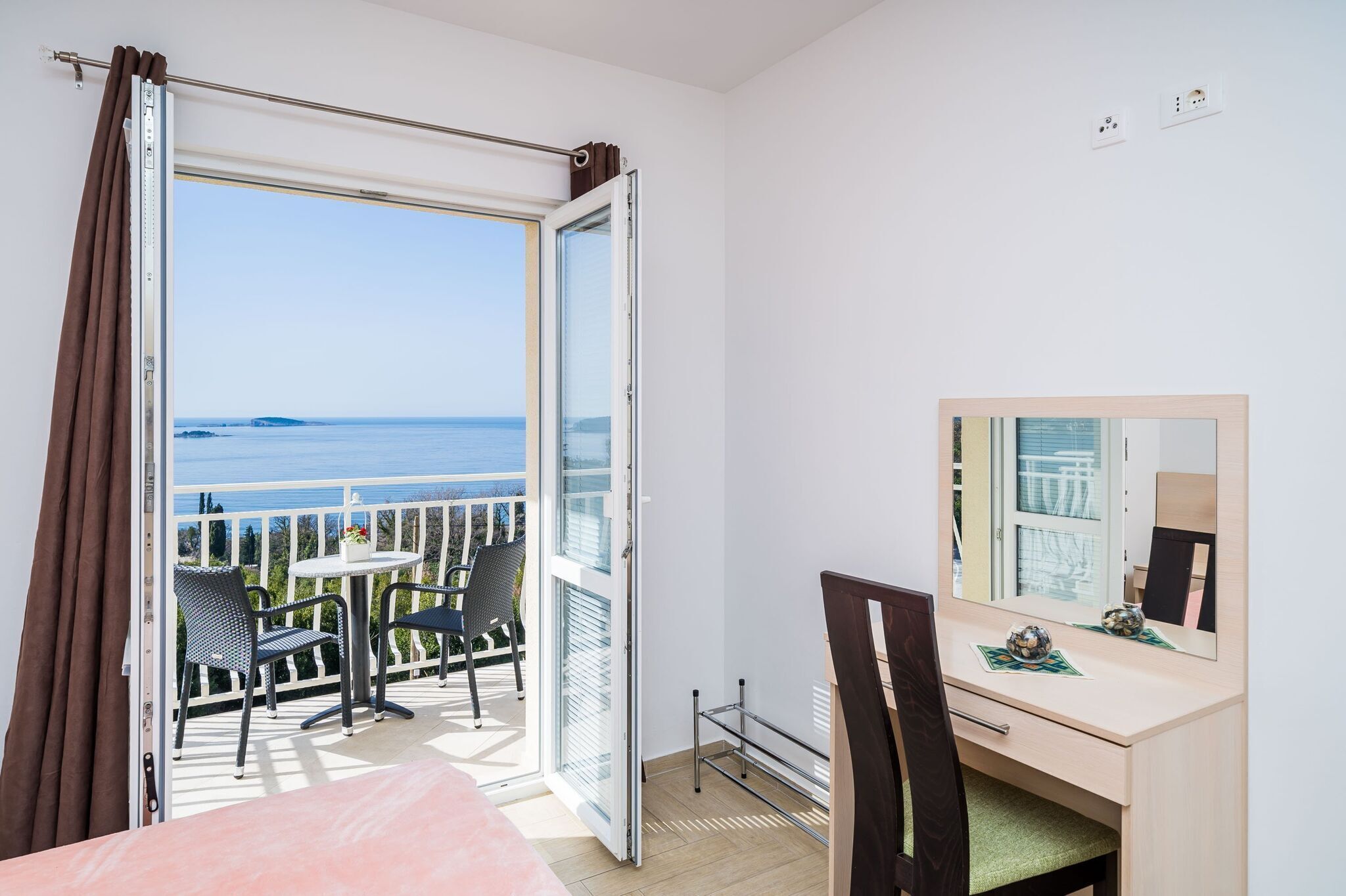 A room with a balcony, a desk, and a chair.