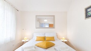 Une chambre d’hôtel avec un lit, deux lampes de chevet, un miroir et une fenêtre avec des rideaux.