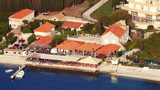 Vue aérienne d’une ville côtière avec ses bâtiments, son front de mer et un restaurant doté d’une terrasse.