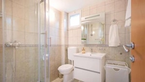 Une salle de bain avec une douche à parois de verre, des toilettes, un lavabo et un miroir.