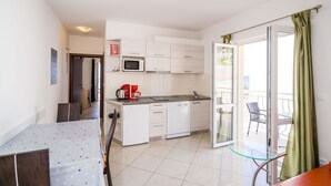Une cuisine moderne avec des meubles blancs, un four à micro-ondes et une machine à café posés sur le plan de travail.