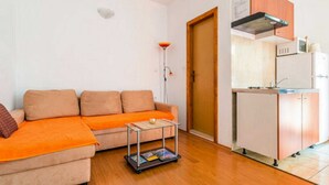 Ett kompakt bostadsutrymme med en soffa, ett litet bord och ett litet kök.