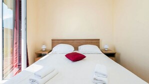Una habitación de hotel con una cama grande, dos mesitas de noche con lámparas y una ventana con persianas.