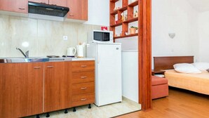 Eine kleine Küche mit Holzausstattung, einem weißen Kühlschrank und einer Mikrowelle.