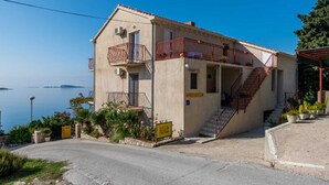 Ein zweistöckiges Gebäude mit Balkon, Treppe und Meerblick.