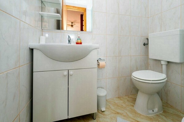 Une salle de bain avec un lavabo blanc, des toilettes et un miroir au-dessus du lavabo.