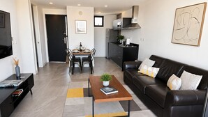 A modern living room with a sofa, coffee table, and dining area. - Distrito Revolution Suites  (Tijuana)