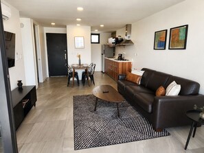 A modern living room with a sofa, coffee table, and dining area. - Distrito Revolution Suites  (Tijuana)