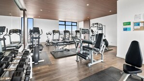 A modern gym with various exercise equipment, large windows, and a wooden ceiling. - Distrito Revolution Suites  (Tijuana)