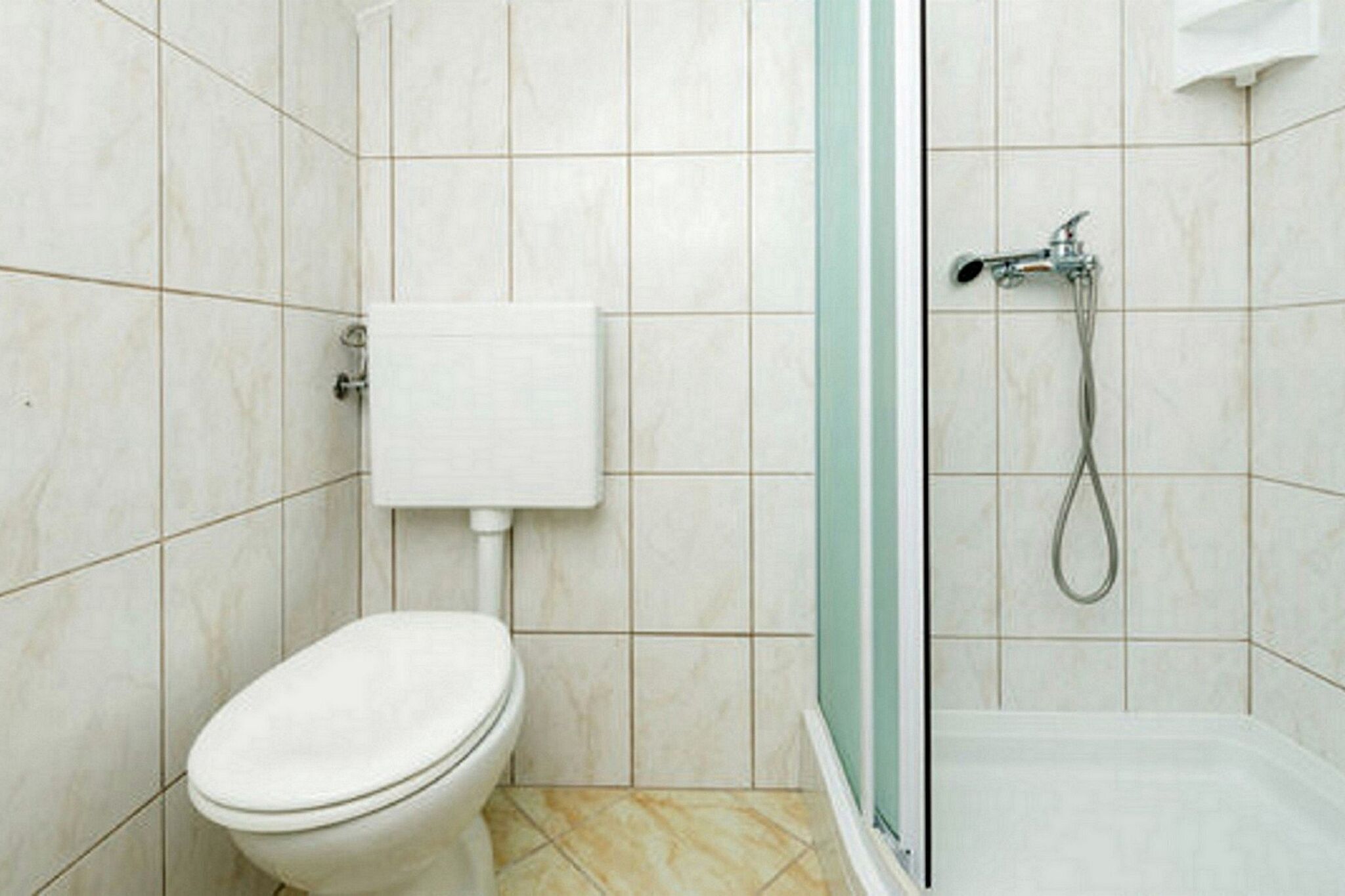 Une salle de bain avec des toilettes, une douche et un sol carrelé.