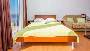 Hotellihuone, jossa on sänky, sohva, ikkuna verhoilla ja näköala.