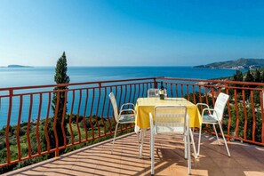 Eine Terrasse mit Tisch und Stühlen mit Blick auf die Küste.