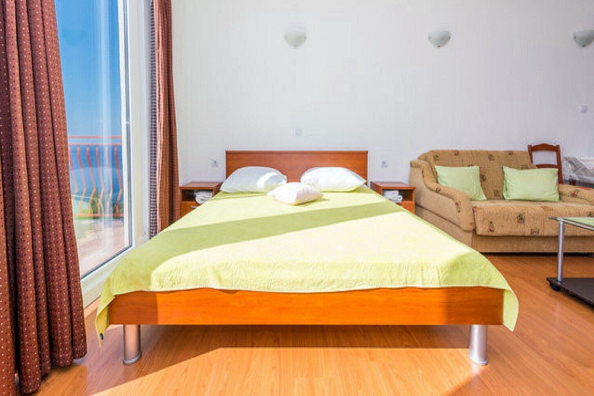 Une chambre d’hôtel avec un lit, un canapé et une fenêtre avec des rideaux.