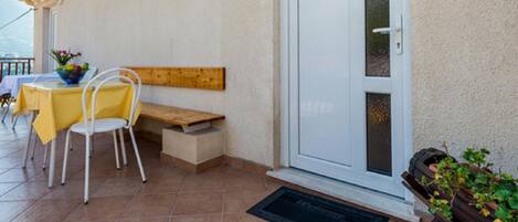 Un patio con tavolo e sedie, una panca e una porta con un pannello in vetro.