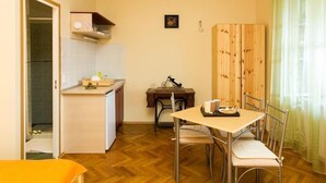 A compact kitchen with a dining area, wooden paneling, and a small table with chairs.