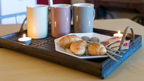 A tray with croissants and a plate of coins on a wooden table.