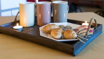 A tray with croissants and a plate of coins on a wooden table.