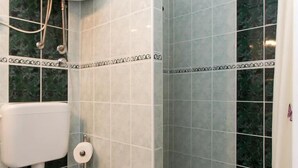 A bathroom with a toilet, a shower, and a sink.