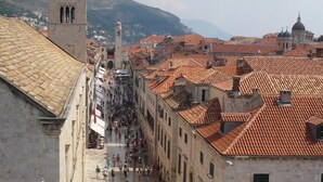 A historic street with traditional architecture, a prominent tower, and a bustling pedestrian area.