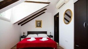 A bedroom with a bed, a nightstand, a wardrobe, a painting, and a mirror.