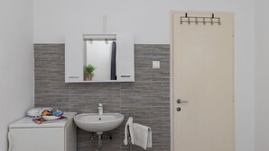A modern bathroom with a white sink, mirror, and cabinet. There is a towel rack with a white towel hanging on it.