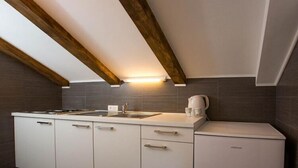 A modern kitchen with white cabinets, a built-in stove, and a coffee maker.