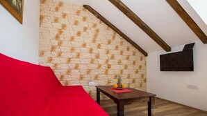 A cozy room with a red sofa, a wooden table with fruit, and a brick-patterned wall.