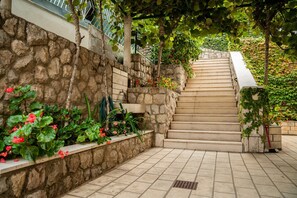 A stone staircase with a tiled floor, surrounded by greenery and flowers.