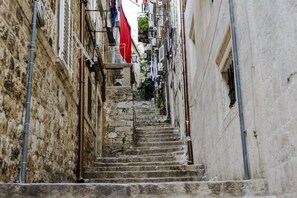 A narrow stone staircase in a historic building with multiple balconies and air conditioning units.