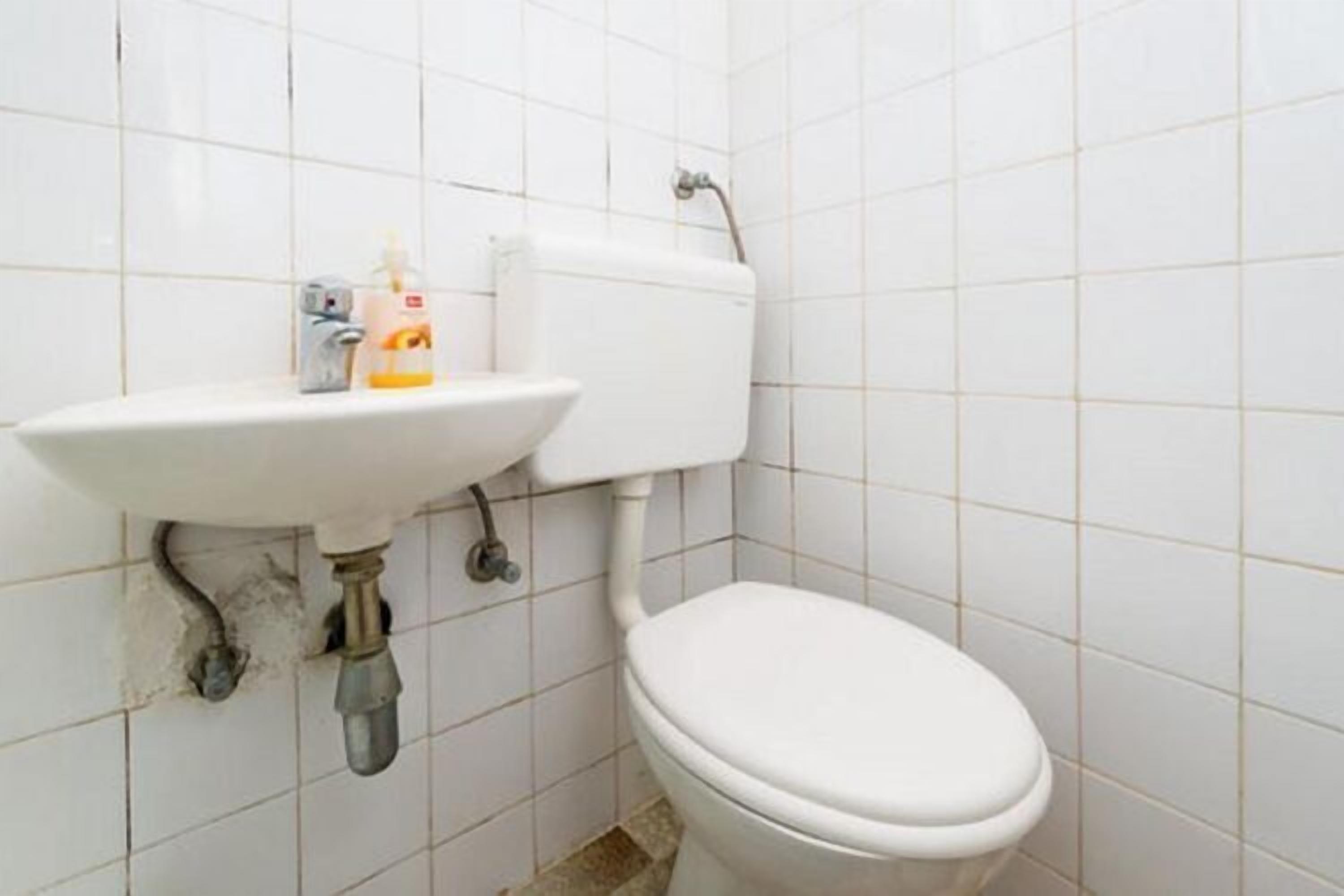 A bathroom with a white toilet, a sink, and a toilet paper holder.