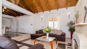 Una sala de estar moderna con chimenea, sofás de cuero, una mesa de centro y techo de madera.