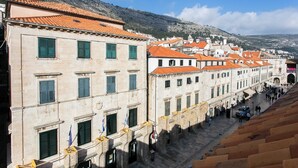 Una calle histórica con arquitectura tradicional, incluyendo edificios de piedra con tejados de tejas rojas y contraventanas verdes.