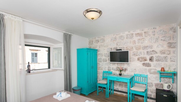 Habitación de hotel con cama, escritorio, dos sillas, televisor, armario y refrigerador pequeño.
