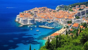 A coastal town with historic buildings, a fortified structure, and a marina.