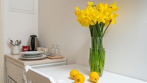 Una encimera de cocina con un jarrón de flores amarillas, una cafetera y dos limones.