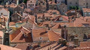 A densely packed urban area with closely built stone and brick buildings, featuring red-tiled roofs.