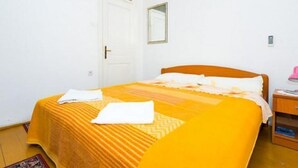 A single-bed room with a wooden headboard, a small bedside table, and a nightstand.