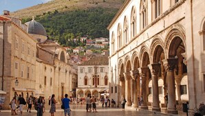 Una plaza histórica con arquitectura clásica, incluyendo arcos y columnas, rodeada de edificios.