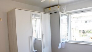 A bedroom with a wardrobe, a window, and a bed.