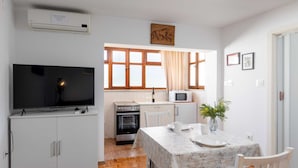 A compact kitchen with a TV, microwave, oven, and a dining area with a table and chairs.