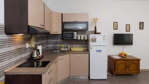 Una cocina compacta con microondas, refrigerador y un pequeño armario de madera.
