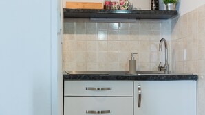A kitchen with a black countertop, stainless steel faucet, and white cabinets. - Apartments Ivana Old Town -Superior Studio - APT2 (Dubrovnik)