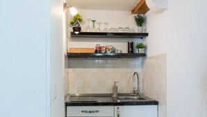 A kitchen with a sink, countertop, and cabinets. There are shelves above the countertop holding various items. - Apartments Ivana Old Town -Superior Studio - APT2 (Dubrovnik)