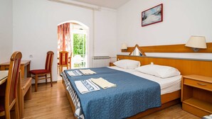 A hotel room with a bed, a desk, a chair, a lamp, and a painting on the wall. - Apartments Klis -Studio Apartment with Terrace - 2 (A) (Soline)
