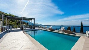 A rectangular pool with a clear blue water surface, surrounded by a tiled deck and lounge chairs. - Apartments Klis -Studio Apartment with Terrace - 2 (C) (Soline)