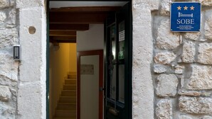 A stone building entrance with a staircase leading inside. A sign on the wall indicates it's a hotel named Sobe. - Apartments Ivana Old Town - Standard Studio - APT3 (Dubrovnik)